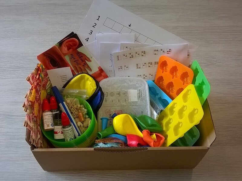 Inhoud van 'Feestje vol zin', met zeep, kleurstof en geurstof, vormpjes, maatbekers, lintjes, zakjes, blinddoeken, servetten, ballonnen, codes, puzzels en spelletjes voor een keitof feestje